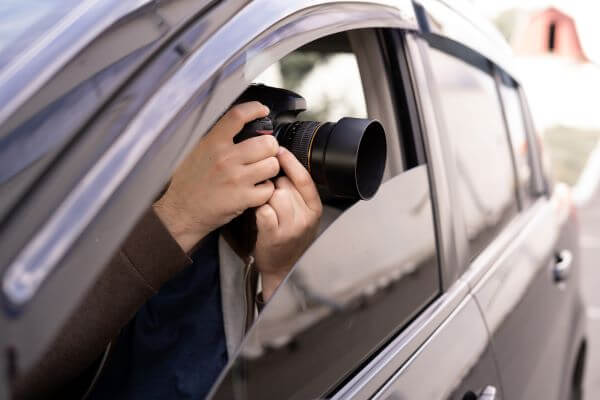 A man pointing a camera out of a car window