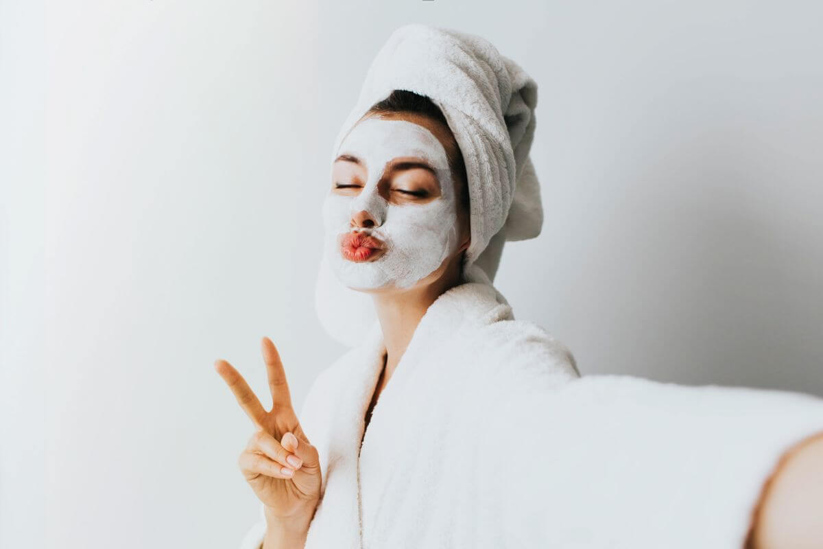 Woman enjoying a simple Korean skincare routine at home with a face mask and towel wrap