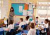Modern Approaches to Special Educational Needs in UK Schools Teacher leading a lesson in a UK primary classroom while pupils in uniform sit at desks with their hands raised
