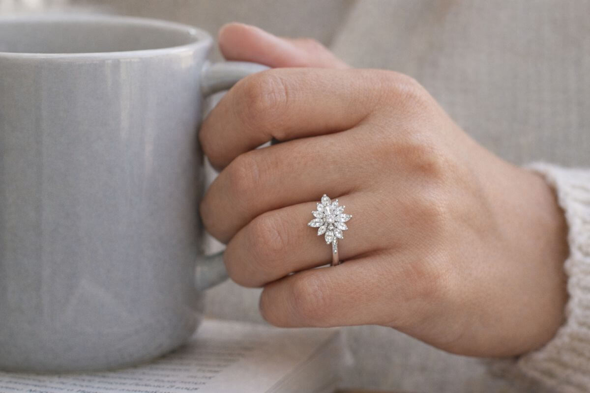 Hand holding coffee mug with sparkling engagement ring
